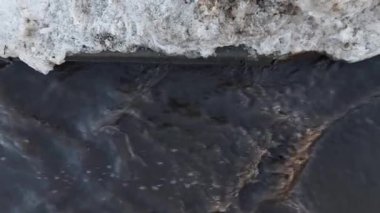 Su birikintisi Kardan eriyen kirli su, yağmur yağdıktan sonra kaldırım boyunca akar. Kış sonrası ilkbahar. Sıfırın üstünde. Kanalizasyon sisteminin kötü işleyişi. Çamurlu. Güneşli bir gün. Üst görünüm