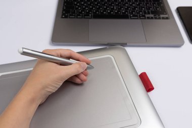 Stüdyoda dijital tablet kalem ve bilgisayar kullanarak grafik tasarımcı elini kapat.