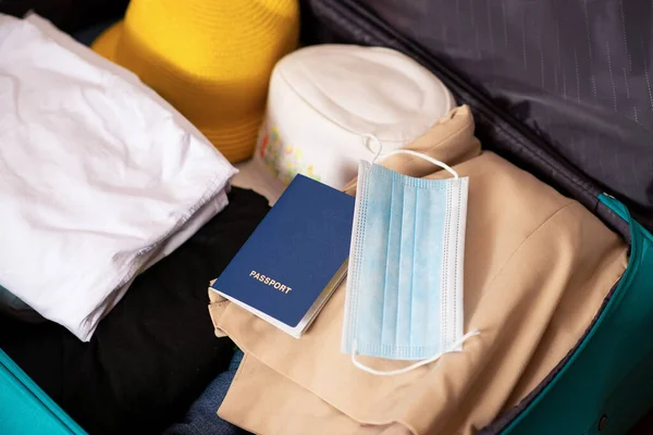 Tampilan puncak koper disiapkan untuk liburan tepi laut selama pandemi. Pakaian, paspor dengan medis dan masker. — Stok Foto