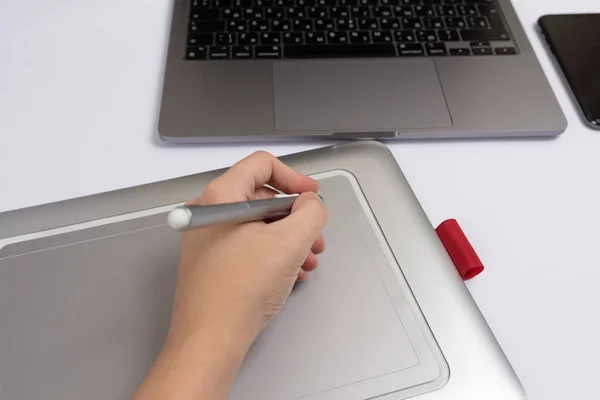 Stüdyoda dijital tablet kalem ve bilgisayar kullanarak grafik tasarımcı elini kapat.