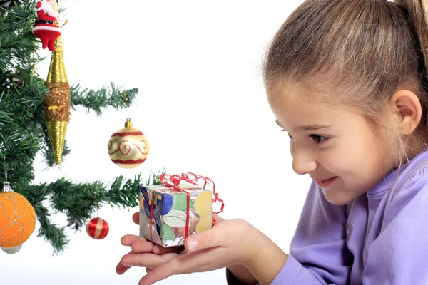Little girl with a gift and Christmas tree — Stock Photo, Image