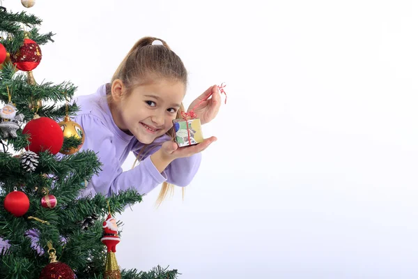 Little girl with a gift and Christmas tree — Stock Photo, Image