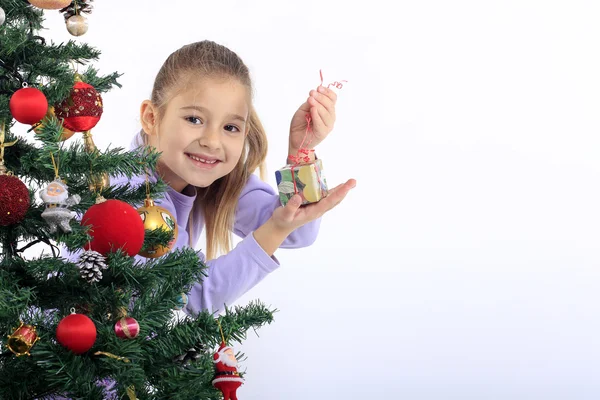 Little girl with a gift and Christmas tree — Stock Photo, Image