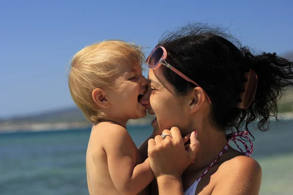 Baby biting her mother's nose — Stock Photo, Image