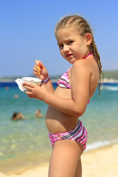 Petite fille manger de la crème glacée sur la plage Photo De Stock