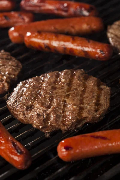 Hamburgers en hotdogs op de grill — Stockfoto