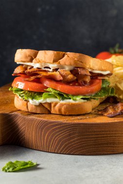 Ev yapımı domuz pastırmalı Marul Domatesli BLT Sandviç ve patates cipsi.