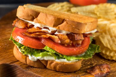 Ev yapımı domuz pastırmalı Marul Domatesli BLT Sandviç ve patates cipsi.