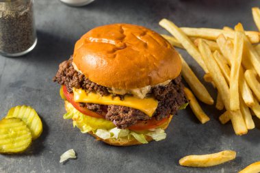 Ev yapımı Cheese Smash Burger yanında patates turşusu ve domates.