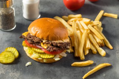 Ev yapımı Cheese Smash Burger yanında patates turşusu ve domates.