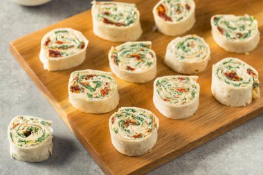 Krem peynirli ve ıspanaklı ev yapımı fırıldak tortilla aperatifleri.