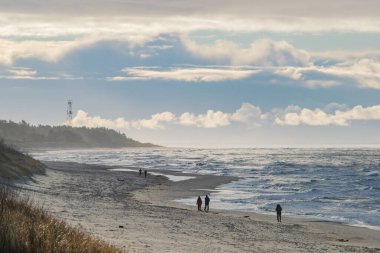 Fırtınalı bir günde Palanga sahillerinde yürüyen insanlar.