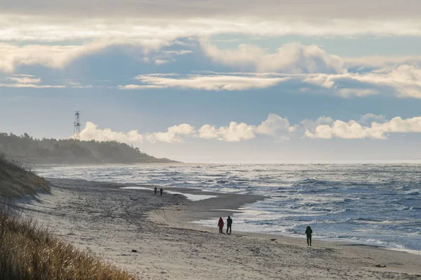 Fırtınalı bir günde Palanga sahillerinde yürüyen insanlar.