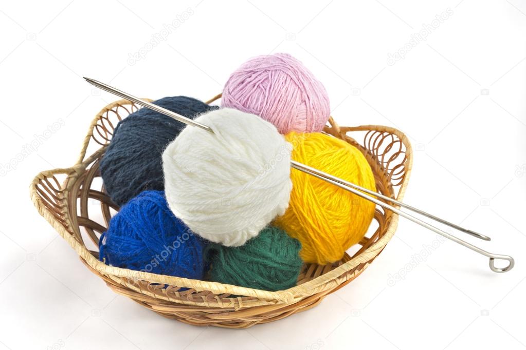 Knitting yarn balls and needles in basket on a white background