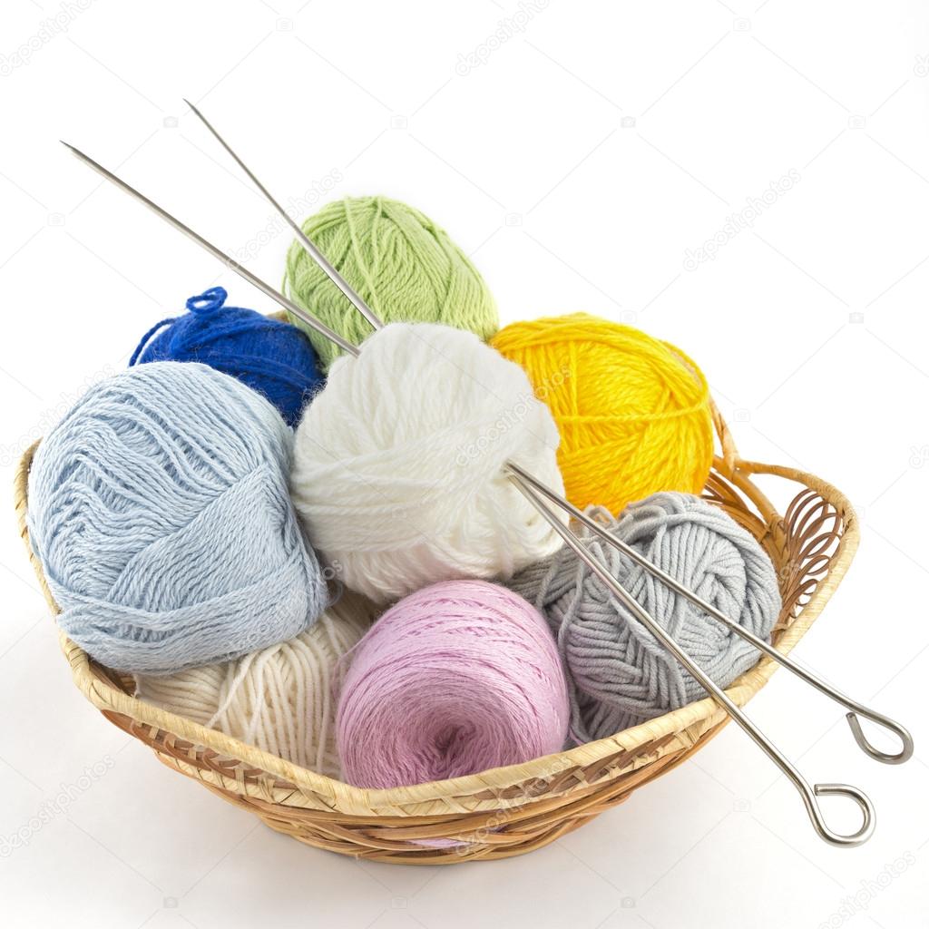 Knitting yarn balls and needles in basket on a white background