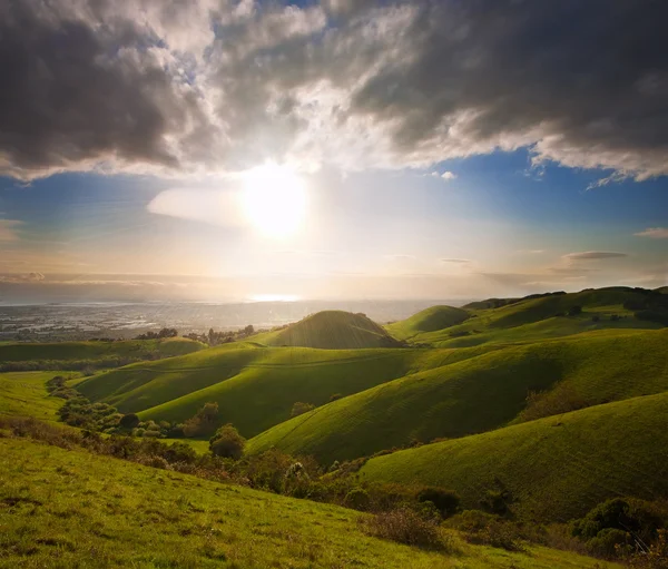 Pôr do sol de primavera sobre colinas verdes — Fotografia de Stock