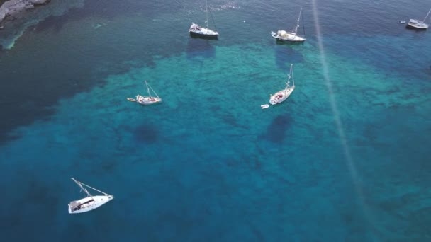 夕日の透明度の高いターコイズブルーの水で湾に停泊するヨットをセーリング 空中ドローンビュー — ストック動画