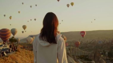 Gün doğumunda Balon Festivali 'ni izleyen genç bir kadının arka görüntüsü