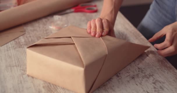 Жінка обгортає святковий подарунок, прикрашаючи стильний подарунок у ремісничому папері — стокове відео