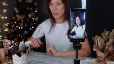 Kadın blogcu, noel zamanı makyaj malzemesi ile video kaydediyor. Çevrimiçi olarak sosyal medya kavramını etkiliyor. Canlı yayın viral