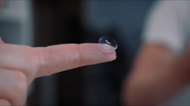İnsan parmağı üzerinde kontak lens, miyop görme konsepti düzeltmesi