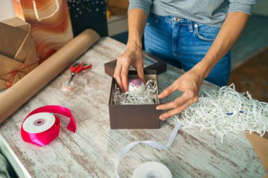 Evdeki masada hediye paketleri paketleyen bir kadın. Dekor elementleriyle doğal eko sunumları hazırlanıyor.