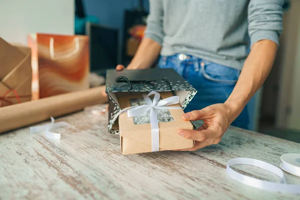 Bayram hediyesini paketliyorum. Evin masasındaki el sanatları kağıdıyla süslenmiş şık bir kadın.