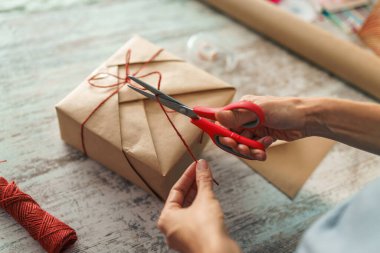 Bayram hediyelerini paketleyen kadın, şık hediyeleri evdeki masada el işi kağıtlarıyla süsleyen kadın.