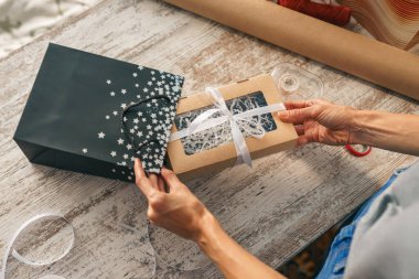 Bayram hediyesini paketliyorum. Evin masasındaki el sanatları kağıdıyla süslenmiş şık bir kadın.