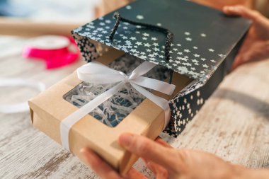 Bayram hediyesini paketliyorum. Kadın Eller şık bir hediyeyi el işi kağıdıyla süslüyor.