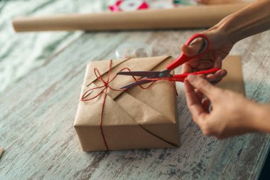 Evdeki masada hediye paketleri paketleyen bir kadın. Hediyeler dekor ögeleri ile hazırlanıyor.