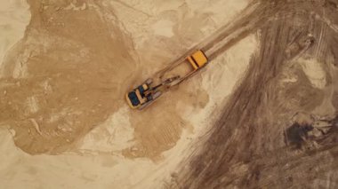 Kazıcı kum ocağındaki bir çöp kamyonuna kum yüklüyor.