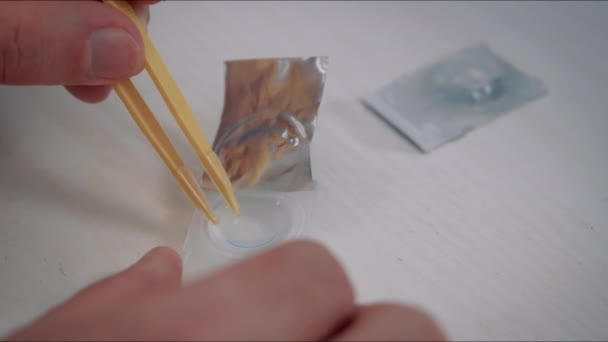 Мужчина берёт контактные линзы из пластикового контейнера — стоковое видео