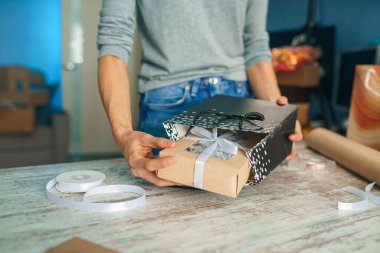 Bayram hediyelerini paketleyen kadın, şık hediyeleri evdeki masada el işi kağıtlarıyla süsleyen kadın.