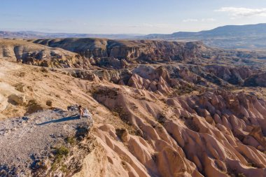 Uçurumda oturan ve Kapadokya 'daki özel dağların manzarasının tadını çıkaran kadın.