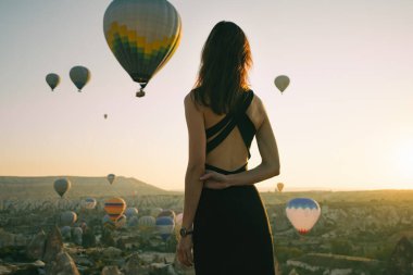 Genç bayan gezgin hava balonlarına bakıyor. Tamamen özgürlük hissi.
