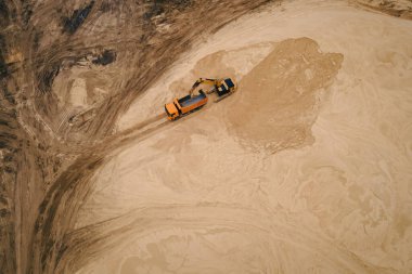Kazıcı kum madenindeki bir kamyona kum yüklüyor. İnşaat endüstrisi için endüstriyel kum çıkarılıyor.