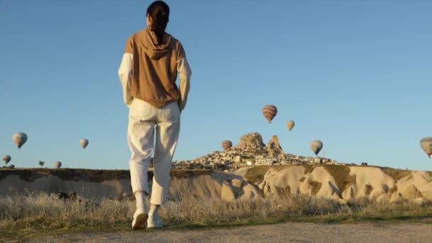 Reisende blickt auf die Luftballons in Kappadokien in der Nähe der Burg Uchisar — Stockvideo