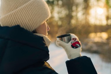 Kış ormanındaki kupadan sıcak çay içen kadın, yakın.