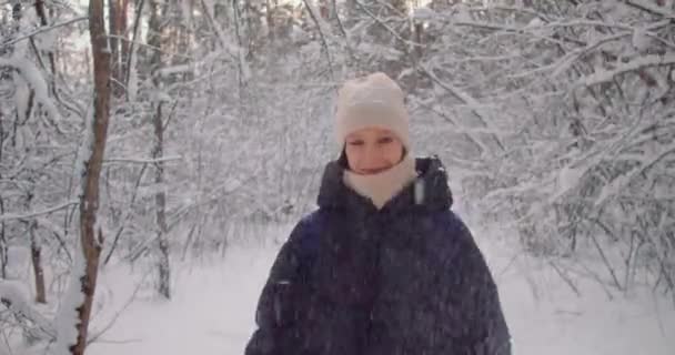 木々の間の雪の中で冬の森の中を歩く面白い幸せな女性 美しい冬の日を楽しむ陽気な女性 — ストック動画