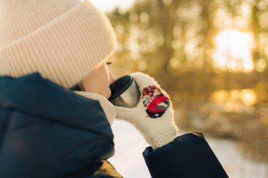 Kış ormanındaki kupadan sıcak çay içen kadın, yakın.