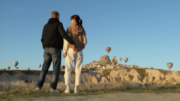 Romantiskt par går i Kappadokien med fluga varmluftsballonger — Stockvideo