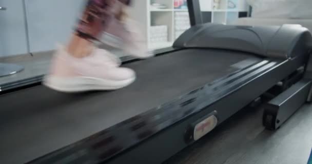 Közelkép női lábak egy futópadon a nappaliban — Stock videók