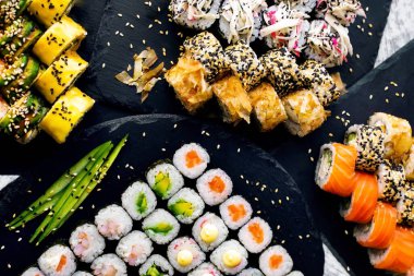 Japon yemeği siyah masa arkasında dört çeşit rulo ekmek.