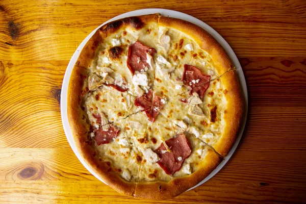 Pizza mit Soße, Huhn, Käse auf Teller auf Holztisch. — Stockfoto