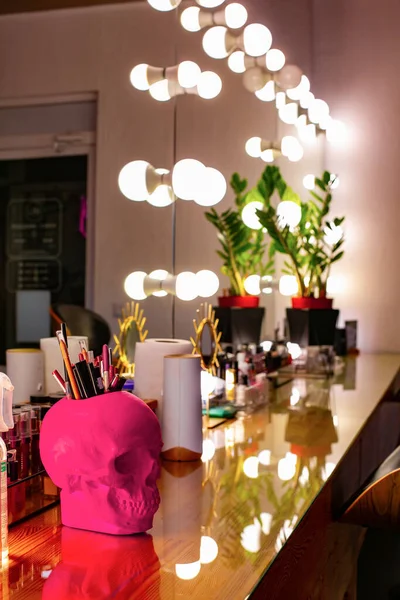 Professional cosmetics on table in hairdressing salon. lightbulb mirror