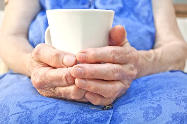 Starszy ręka trzymać filiżankę herbaty — Zdjęcie stockowe