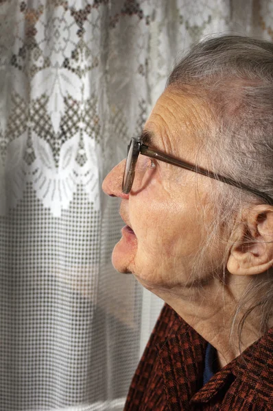 Oude vrouw in het venster — Stockfoto