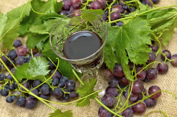 Rotwein im Weinglas mit süßen Trauben. — Stockfoto