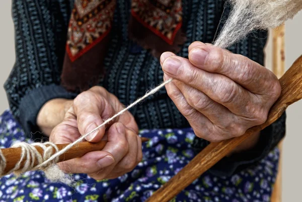 Oude handen spinnen van wol. — Stockfoto